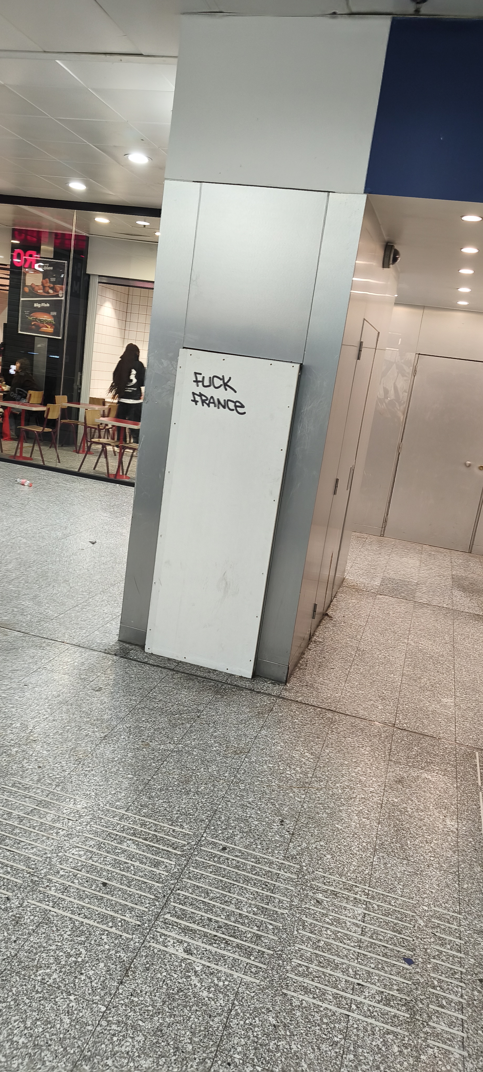 phone photo showing showing a small grafiti on an interior wall with the text "FUCK FRANCE"